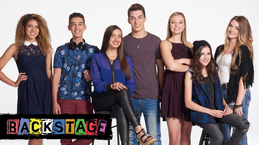 A group of teenagers standing and sitting next to each other in front of a white background