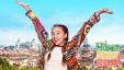 a girl in a colourful sweater raising her arms above her head in front of the skyline of Rome